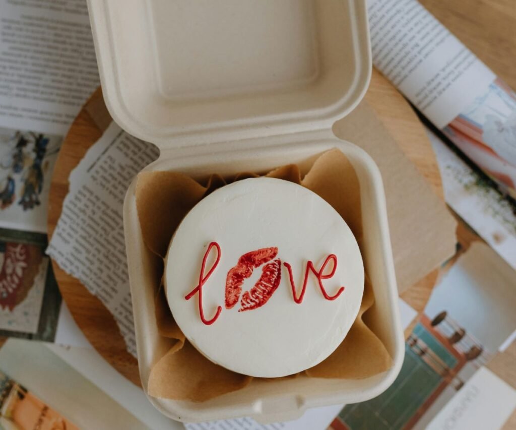 Valentine's Day cake with red love text and lipstick kiss decoration in white takeout box